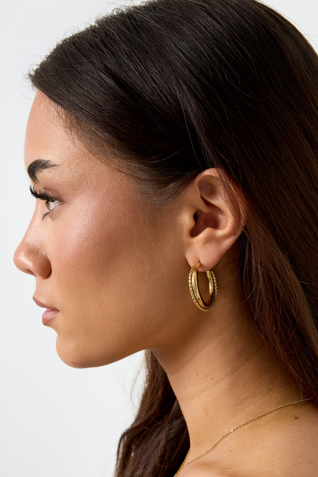 Damen trägt doppelte Creolen mit gedrehtem Detail im modernen Look